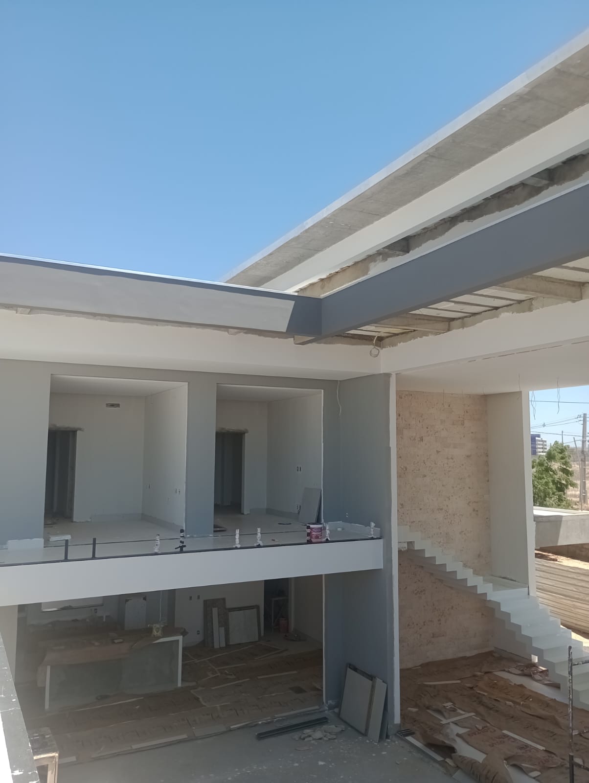 Residência em fase final de pintura com paredes e vigas em branco e cinza